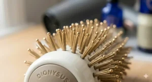 Extreme macro photograph focusing on the gold-tipped bristles of a professional white ceramic hairbrush used for ionic blow-drying.