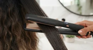Close-up of wide plate straighteners smoothing a section of long hair