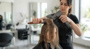 Stylist using a round brush for volume to lift fine hair at the crown for added bounce