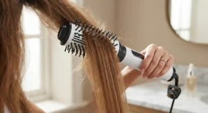 Close-up of a ceramic hot air brush smoothing and straightening frizzy hair strands effortlessly