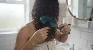 Woman styling her natural hair using an anti-frizz wet brush for curly hair for a smooth finish.