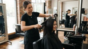 A stylist using a pure boar bristle brush to add glossy shine to dry hair styling.