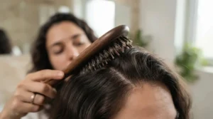 Demonstrating a scalp massage using a firm synthetic bristle brush for deep cleansing.